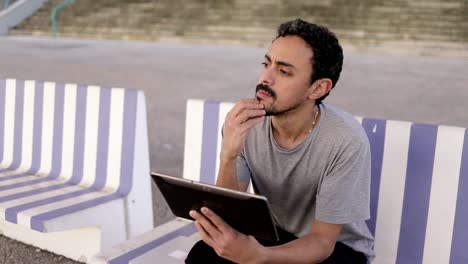Thoughtful-man-with-digital-tablet-on-street